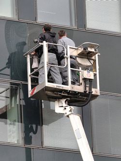 zwei Reinigungsunternehmen Mitarbeiter im Kran reinigen Fassade eines Hochhauses in Frankfurt