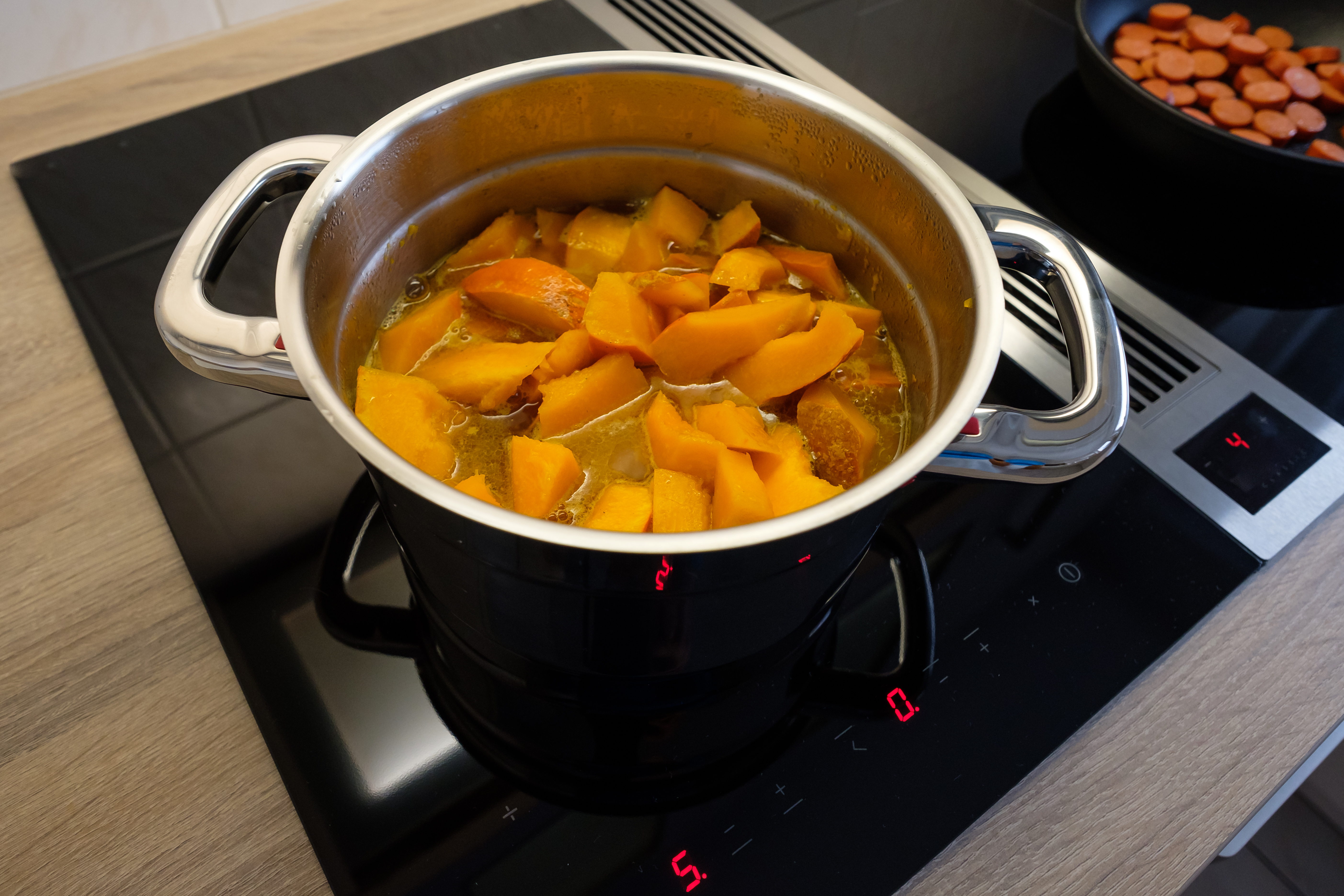 Kürbis im kochenden Topf auf modernem Induktionskochfeld mit Blick auf elegante Kochfläche und Kochfeldumgebung.